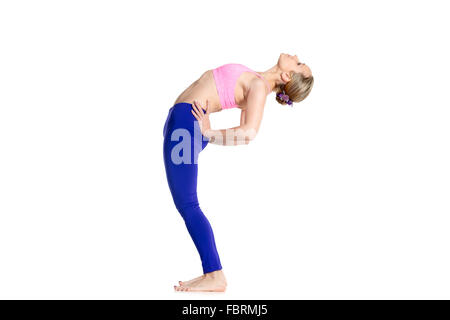 Sporty beautiful young blond woman doing Standing Backward Bend yoga posture, Ardha Chakrasana, Half Wheel pose, studio Stock Photo