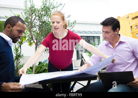 Businesswoman showing colleagues blueprint Stock Photo