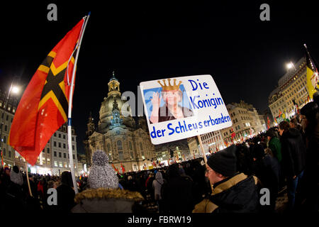 Dresden, Germany. 18th Jan, 2016. Demonstrators hold up a sign depicting German Chancellor Angela Merkel wearing a crown that reads 'The queen of trafficker gangs' during a rally of the far-right Pegida (Patriotic Europeans against the Islamization of the Occident) movement in front of the Frauenkirche church in Dresden, Germany, 18 January 2016. Photo: ARNO BURGI/dpa/Alamy Live News Stock Photo