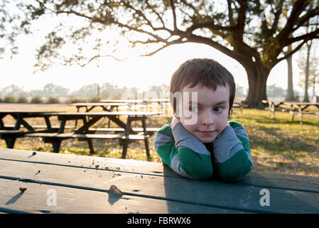 Boy sitting at picnic table in park, portrait Stock Photo