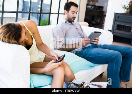 Couple using wireless devices at home Stock Photo