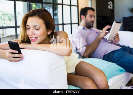Couple using wireless devices at home Stock Photo