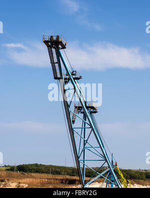 the top platform huge boom clay mining excavator on blue sky background Stock Photo