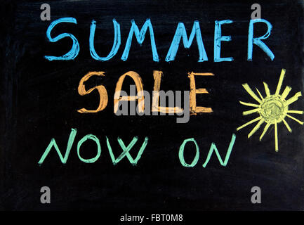 Written summer sale now on on the blackboard Stock Photo