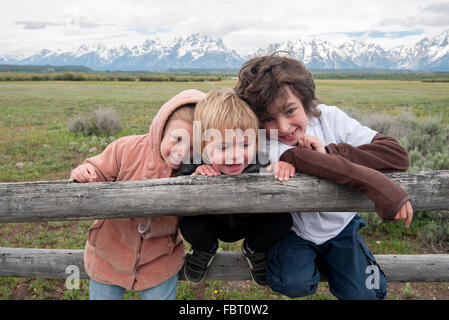 Children leaning against fence in Grand Teton National Park, Wyoming, USA Stock Photo