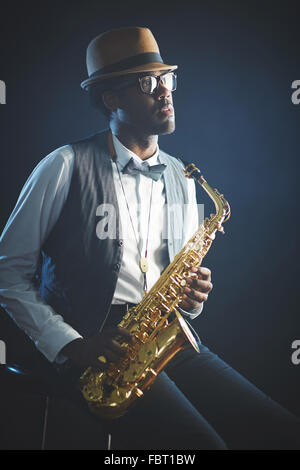 Elegant jazzman in smart clothes and hat holding saxophone Stock Photo
