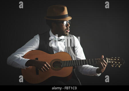 Elegant young man playing guitar in isolation Stock Photo