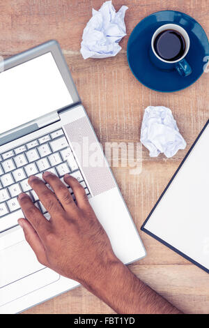 Stressed businessman using laptop by coffee at desk Stock Photo