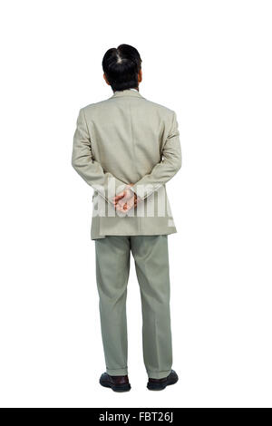 Businessman standing and looking with hands behind back Stock Photo