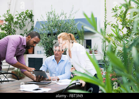 Businessman presenting ideas displayed on digital tablet to colleagues Stock Photo