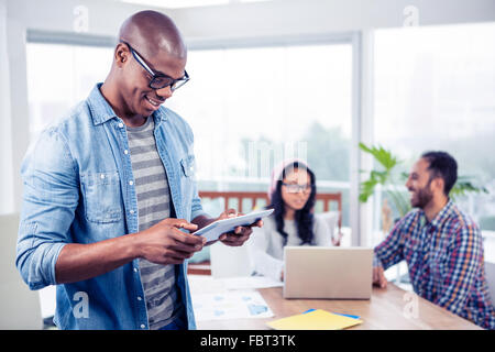 Young businessman using digital tablet while standing in office Stock Photo