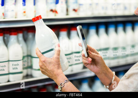 Close up of senior woman taking picture of milk bottle Stock Photo