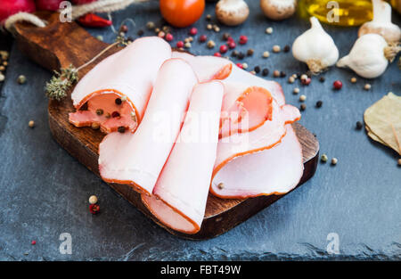 Pork ham slices with ground pepper spice and dried thyme on wooden cutting board Stock Photo