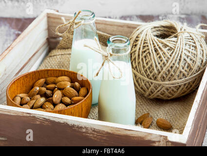 Almond milk in bottles with almond nuts bowl in wooden box Stock Photo