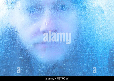 Winter man looking through window covered in ice and condensation UK Stock Photo