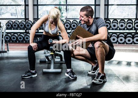 Fit woman doing dumbbells exercise with trainer Stock Photo