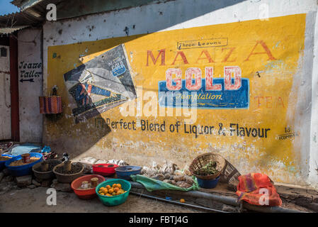 Various plastic bowls of fruit and vegetables line the floor in front of a large bold yellow Maaza Gold Tea blend wall mural. Stock Photo