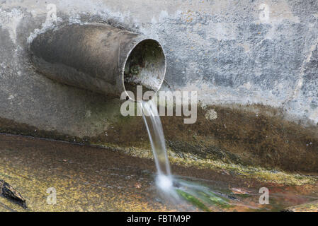 Drainage pipe protruding from a concrete wall into a stream Stock Photo ...