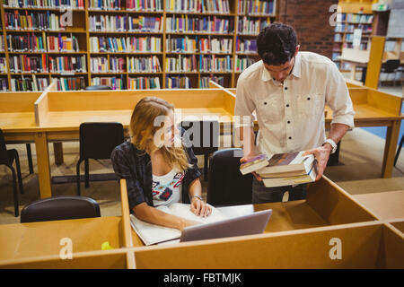 Smiling students working together while sitting at table Stock Photo