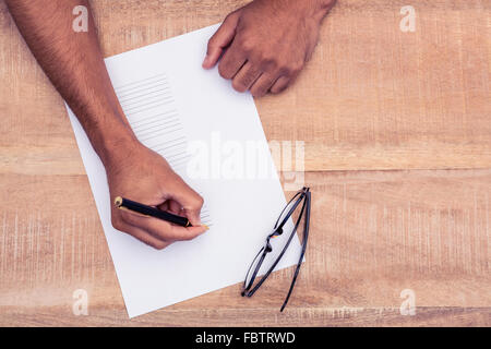 Businessman writing on paper at desk Stock Photo