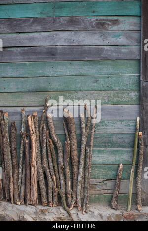Faded wooden boards on a rustic weathered house. All aqua and blue green hues.  Sticks and logs propped up against the wall. Nagaland, India Stock Photo