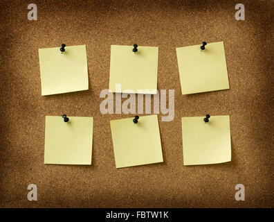 six yellow notes pinned to grunge cork background Stock Photo