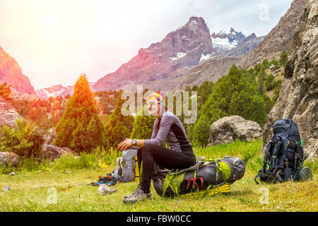 Portrait of female backpacker sitting on her large alpine backpack Stock Photo