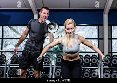 Male trainer motivating fit woman with megaphone Stock Photo