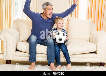 Father and son exulting on the sofa Stock Photo