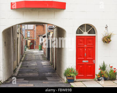 A white painted terraced house in Hartlepool with a bright red front door and adjoining alleyway Stock Photo