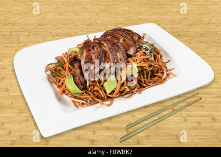 Chinese Food, Roast duck with fried noodles vegetables and gravy. Background Wood with Chopsticks. Stock Photo