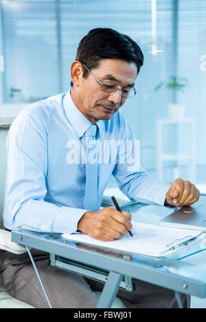 Focused asian businessman writing Stock Photo
