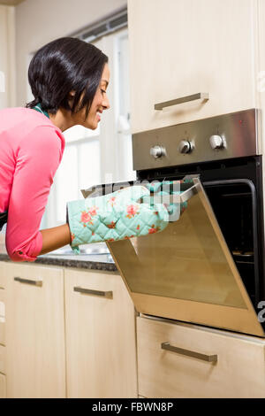 Smiling woman looking in the oven Stock Photo