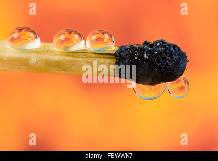 Extinguished Burnt down match with flames of fire refraction in water drops Stock Photo