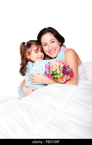Child gives flowers to mother in bed