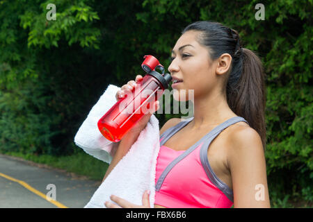 Woman drinks water and rests after running Stock Photo