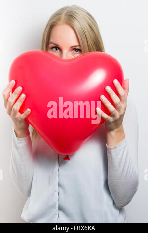 Woman hiding her face behind a red heart Stock Photo