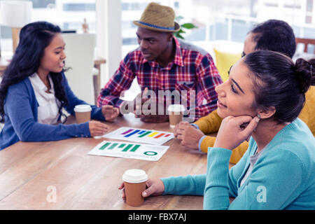Smiling businesswoman day dreaming with colleagues in background Stock Photo