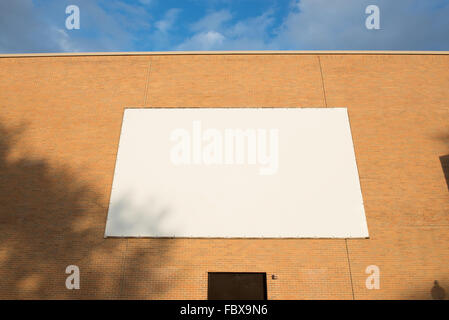 big white blank billboard attached to brown brick wall over a door with shadow Stock Photo