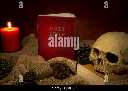 Still life red holy bible and human skull, lighting candle Stock Photo