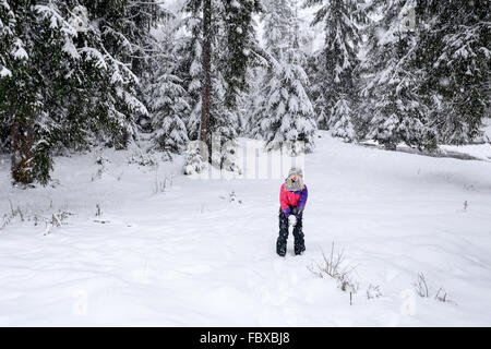 Girl play snowballs in winter snow-covered forest Stock Photo