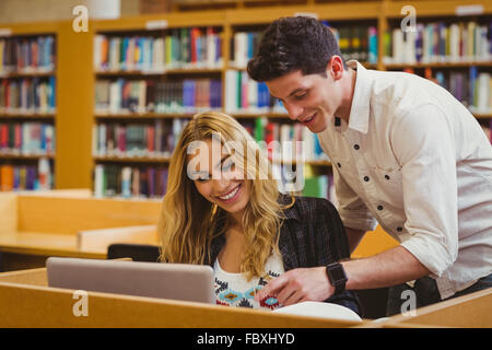 Smiling students working together while sitting at table Stock Photo