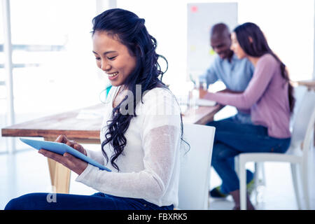 Young businesswoman using tablet PC with colleagues in background Stock Photo