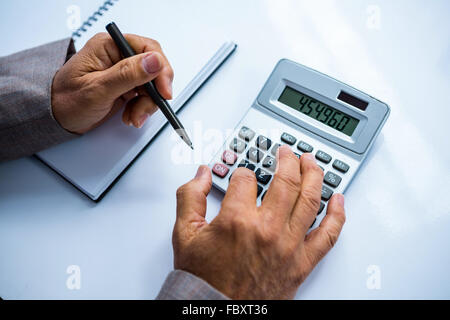 Businessman using calculator and taking notes Stock Photo