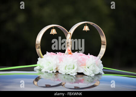 Gold rings and rose flowers on wedding car Stock Photo