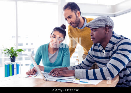 Business man using laptop with colleagues in background Stock Photo