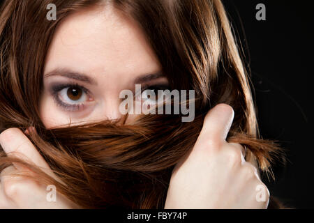 Closeup woman covers the face by long brown hairs