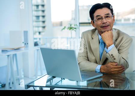 Smiling asian businessman working on laptop Stock Photo