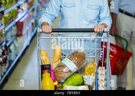 Smiling senior woman pushing cart Stock Photo