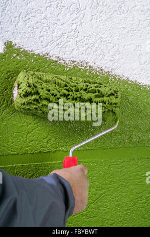 A red paint roller applying color to wooden surface with vivid texture ...